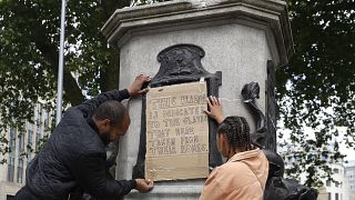 A banner is taped over the inscription on the pedestal of the toppled statue of Edward Colston in Bristol, England, Monday, June 8, 2020