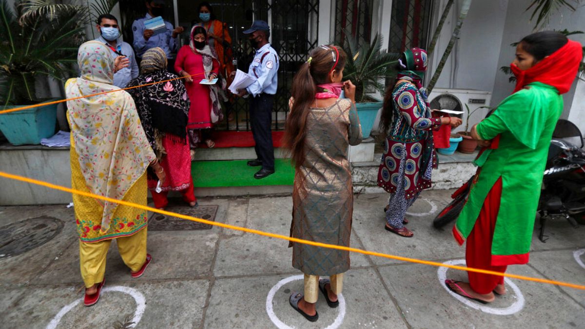 Indians queue up outside a bank to withdraw money during lockdown in Jammu, India, Tuesday, April 7, 2020. 