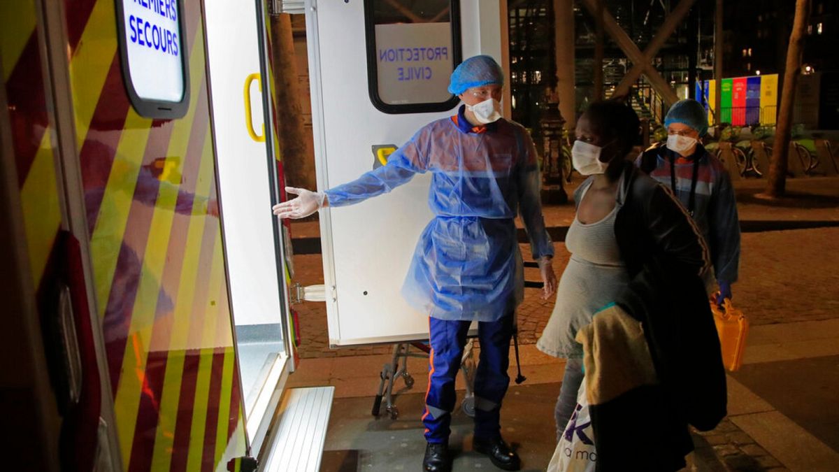First aiders escort a pregnant woman suspected of coronavirus infection infection to an ambulance in Paris, Thursday, March 26, 2020.