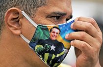 Brezilya Başkanı Jair Bolsonaro resimli maske takan bir kişi