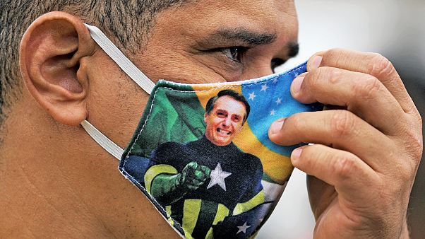 Brezilya Başkanı Jair Bolsonaro resimli maske takan bir kişi Brezilya Başkanı Jair Bolsonaro resimli maske takan bir kişi