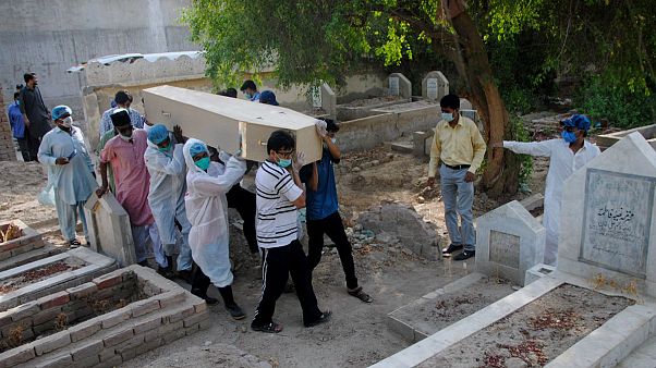 Rescue workers and family members carry the casket of Khursheed Bibi, who died due to coronavirus, for her burial at a cemetery in Hyderabad, Pakistan Rescue workers and family members carry the casket of Khursheed Bibi, who died due to coronavirus, for her burial at a cemetery in Hyderabad, Pakistan