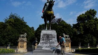 An employee of the city of Brussels cleans up the defaced statue of King Leopold II of Belgium in Brussels on June 10, 2020. 