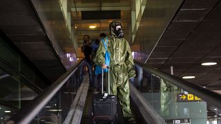 A passenger wearing a protective suit arrives from London at the Barcelona airport, Spain, on Friday, May 15, 2020. 