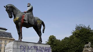 A statue of Belgium's King Leopold II is smeared with red paint and graffiti in Brussels.