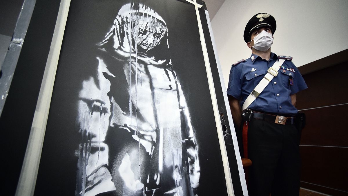 Csendőr őrzi a Banksy-művet az ügyészségi sajtóértekezleten, L'Aquilában