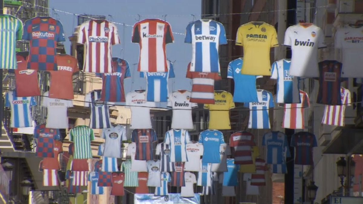 Jerseys of Spanish top tier football clubs hang over Preciados Street, a popular shopping street in Madrid