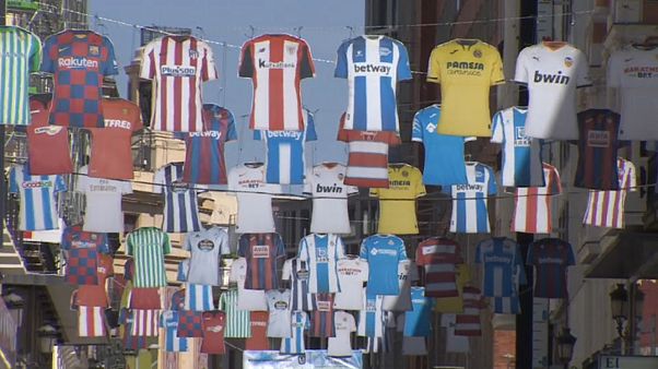 Jerseys of Spanish top tier football clubs hang over Preciados Street, a popular shopping street in Madrid Jerseys of Spanish top tier football clubs hang over Preciados Street, a popular shopping street in Madrid