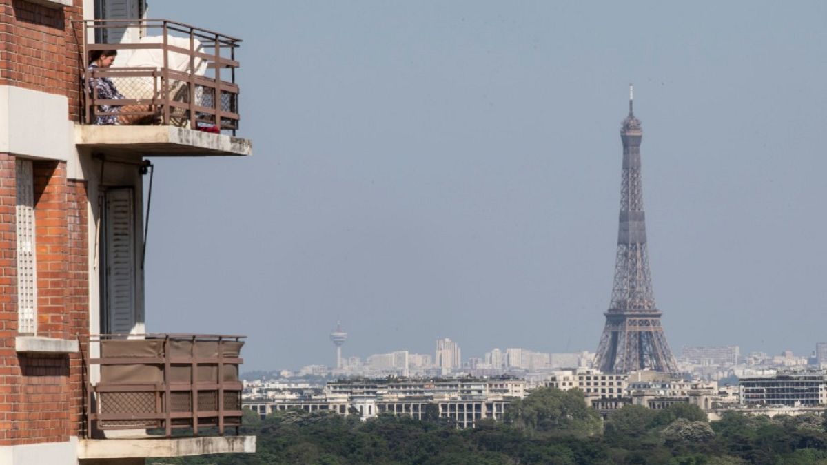 Una donna si gode il sole sul balcone, mentre la Torre Eiffel è chiaramente visibile sullo sfondo. L'inquinamento atmosferico è diminuito a Parigi, durante il confinamento
