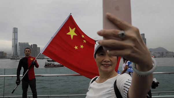 Pro-China supporters take a selfie with a Chinese national flag to support police and anti-violence during a rally at a park in Hong Kong. Pro-China supporters take a selfie with a Chinese national flag to support police and anti-violence during a rally at a park in Hong Kong.