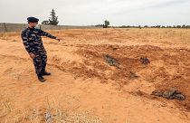 A member of security forces affiliated with the Libyan Government of National Accord (GNA)'s Interior Ministry points at the reported site of a mass grave in town Tarhuna