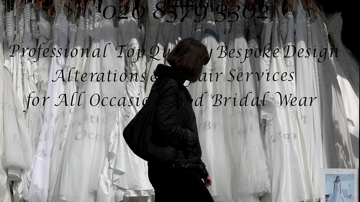 woman walks past a Wedding dress shop in London, Tuesday, June 9, 2020, where bride dresses pile unused in the shop window. 