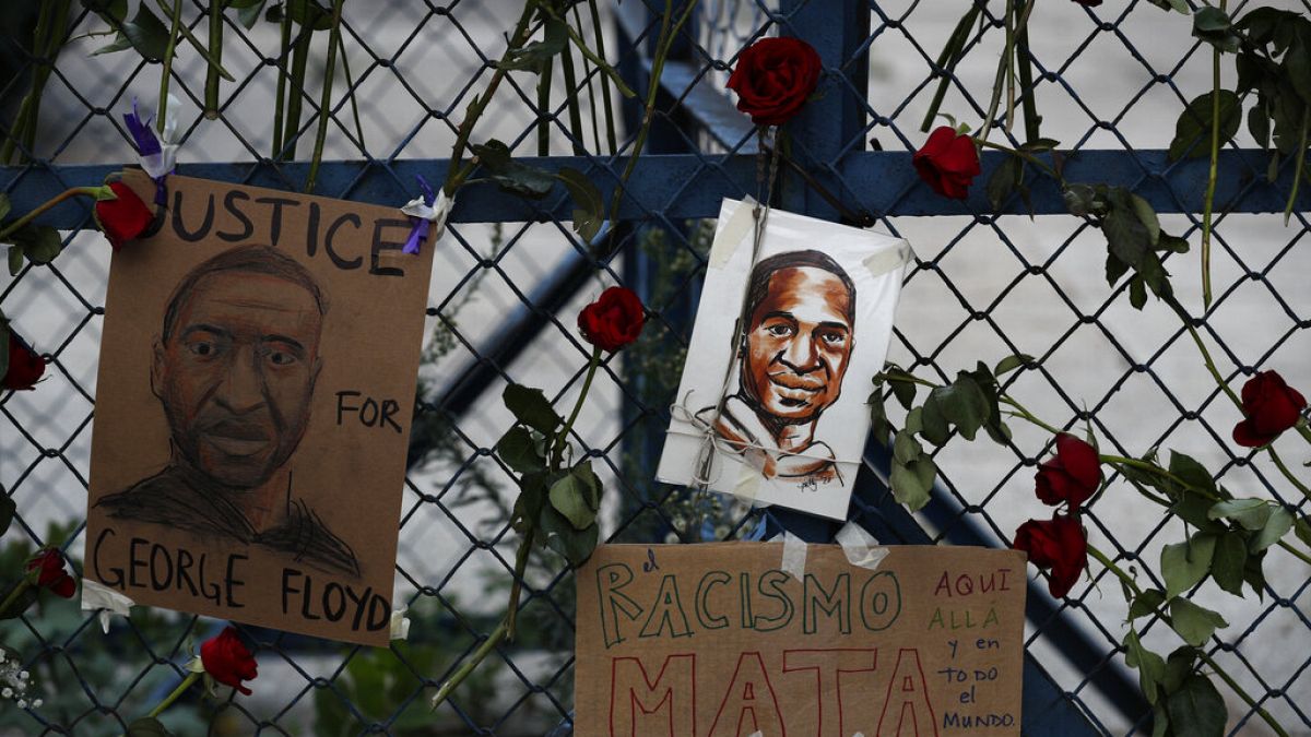 Images of George Floyd hang surrounded by roses on a security barrier outside the US embassy in Mexico City
