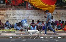 Migrant workers from other states rest on a pavement as they wait for trains to their home states in Hyderabad, India