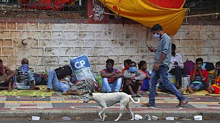 Migrant workers from other states rest on a pavement as they wait for trains to their home states in Hyderabad, India
