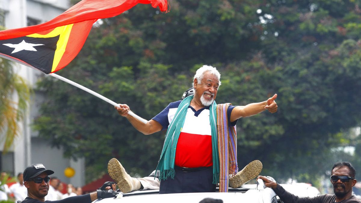 East Timorese independence hero Xanana Gusmao, center, waves a national flag upon arrival in Dili, East Timor, Sunday, March 11, 2018