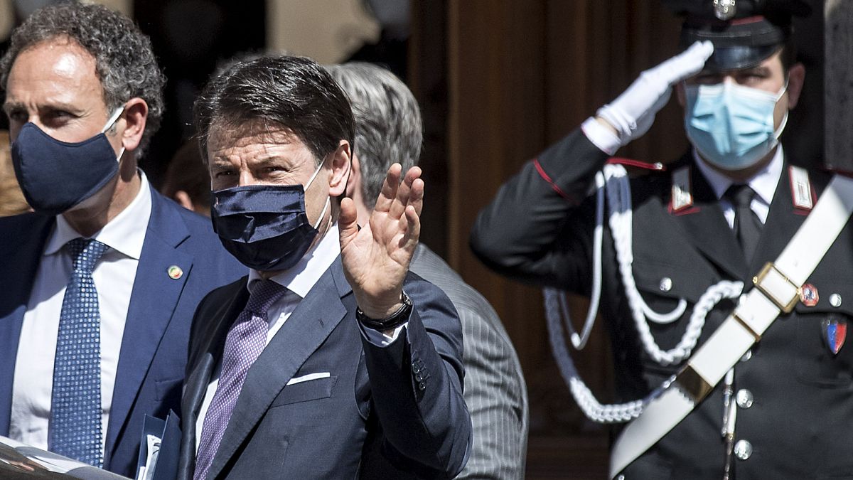 Italian Premier Giuseppe Conte, center, wears a face mask to prevent the spread of COVID-19 as he leaves after addressing parliament at the Senate, in Rome, May 21, 2020.