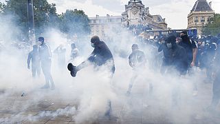 A man kicks a tear gas canister during a march against police brutality and racism in Paris, France, Saturday, June 13, 2020