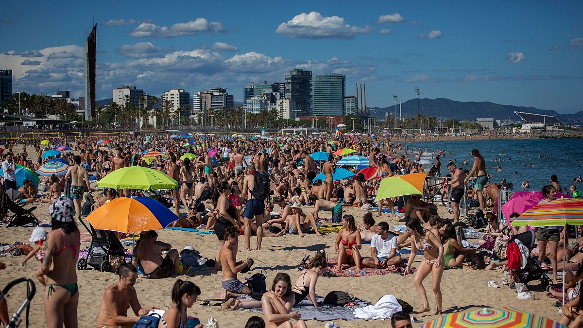 People enjoy the warm weather on the beach in Barcelona, Spain