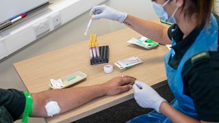 A paramedic carries out a blood draw during an antibody testing programme in Birmingham, England, on June 5, 2020