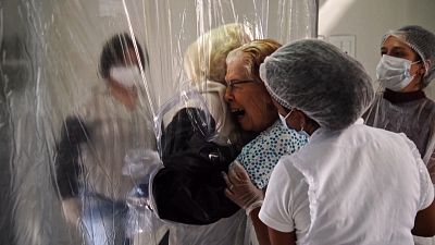 Mid shot, a patient at 3i Senior Residential Welfare, hugs through the 'hug curtain' another woman there to visit her