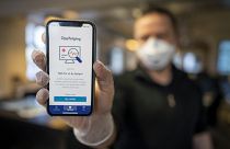 A man holds a mobile phone showing Norway's National Institute of Public Health new mobile app infection stop for infection tracking, in Oslo, Norway, Friday April 17, 2020