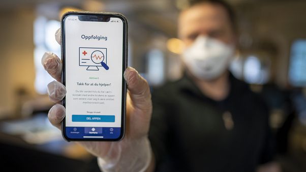 A man holds a mobile phone showing Norway's National Institute of Public Health new mobile app infection stop for infection tracking, in Oslo, Norway, Friday April 17, 2020 A man holds a mobile phone showing Norway's National Institute of Public Health new mobile app infection stop for infection tracking, in Oslo, Norway, Friday April 17, 2020