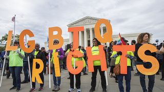 FILE - In this Oct. 8, 2019, file photo, supporters of LGBTQ rights hold placards in front of the U.S. Supreme Court in Washington.