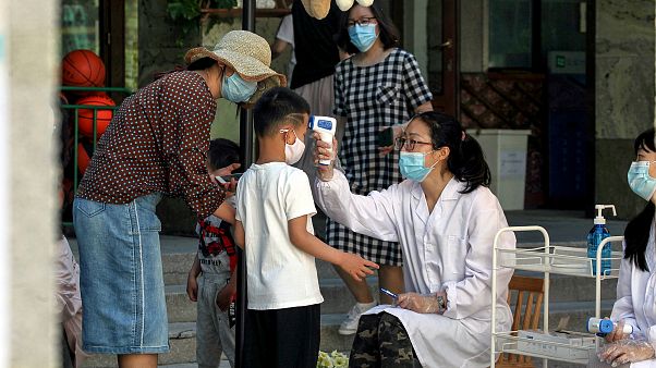 Toman la temperatura a un niño a la entrada de una guardería en China Toman la temperatura a un niño a la entrada de una guardería en China