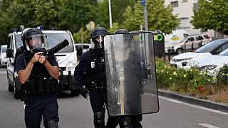 Police walk carrying a shield and a tear gas canister launcher in the Gresilles area of ​​Dijon, eastern France, on June 15, 2020.