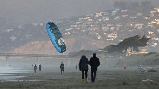 A windsurfer reels in his kite at New Brighton Beach in Christchurch, New Zealand, Tuesday, June 9, 2020.