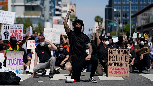 Des manifestants s'agenouillent dans un moment de silence devant le commissariat de Long Beach, le 31 mai 2020, lors d'une manifestation en mémoire à George Floyd. Des manifestants s'agenouillent dans un moment de silence devant le commissariat de Long Beach, le 31 mai 2020, lors d'une manifestation en mémoire à George Floyd.