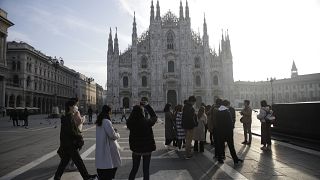 Tourists take pictures of the Duomo gothic cathedral in Milan, Italy, Sunday, Feb. 23, 2020