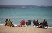 Tourists sit at the beach of Palma de Mallorca, Spain, Tuesday, June 16, 2020.