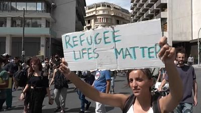 Una manifestante alza un cartel con el eslogan "La vida de los refugiados importa"