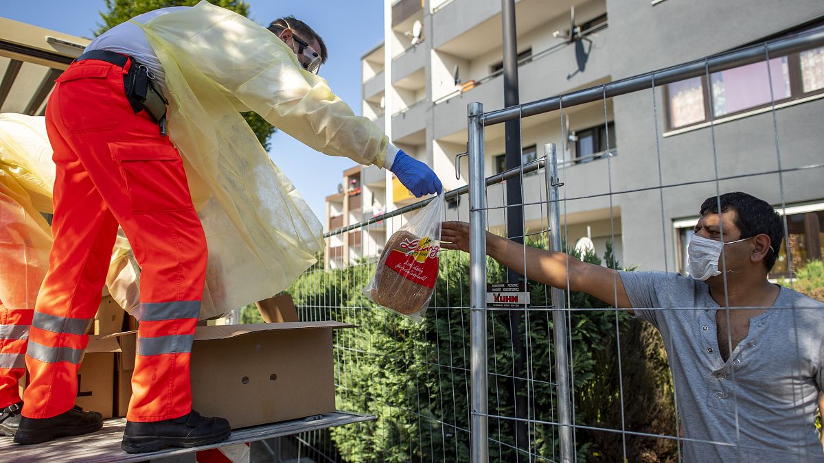 Red Cross helpers wear face masks and protective clothing while distributing bread to residents of a house that has been quarantined in Verl, Germany, Sunday, June 21, 2020. 