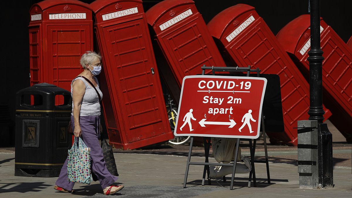A sign requesting people stay two metres apart to try to reduce the spread of COVID-19 is displayed in front of "Out of Order" a 1989 red phone box sculpture