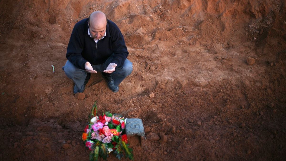 A Libyan man prays for a relative, one of many discovered in a mass grave, 