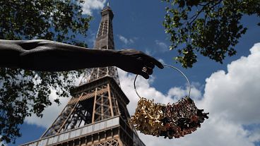 A street vendor displays miniatures of the Eiffel Tower outside of the closed monument in Paris. The iconic structure has been closed for more than three months since March.