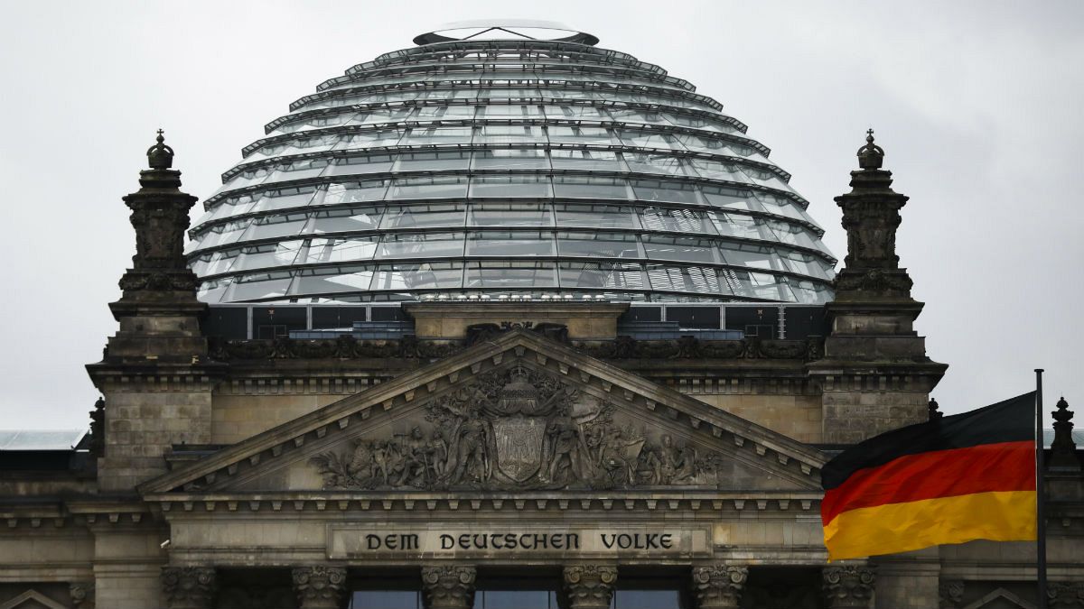 A German national flag waves in front of the German parliament building Reichtstag in Berlin, Germany