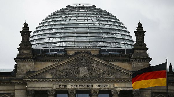 A German national flag waves in front of the German parliament building Reichtstag in Berlin, Germany A German national flag waves in front of the German parliament building Reichtstag in Berlin, Germany