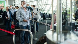 Passengers, wearing face masks to protect against the spread of coronavirus, queue up to board their plane at the Zaventem international airport. Brussels, Belgium