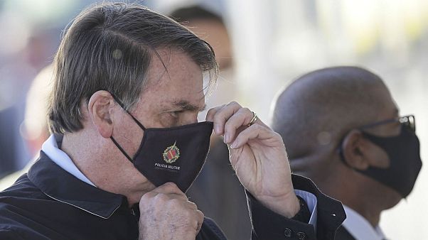 Brazil's President Jair Bolsonaro adjusts his face mask as he speaks to supporters while departing his official residence, Alvorada palace, in Brasilia, Brazil, Thursday, May Brazil's President Jair Bolsonaro adjusts his face mask as he speaks to supporters while departing his official residence, Alvorada palace, in Brasilia, Brazil, Thursday, May