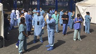 Juarez public hospital health workers wait on a street after a 7.5 earthquake sent them out from their work areas, in Mexico City, Tuesday, June 23, 2020. 