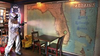 Un dirigeant d'une fabrique de désinfectants asperge symboliquement une carte de Floride dans un bar de St. Petersburg - Floride -, le 24 juin 2020