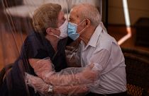 Agustina Cañamero, 81, and Pascual Pérez, 84, hug and kiss through a plastic film screen to avoid contracting the new coronavirus at a nursing home in Barcelona, Spain
