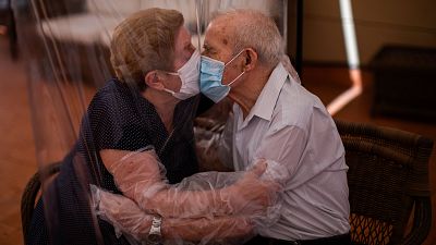 Agustina Cañamero, 81, and Pascual Pérez, 84, hug and kiss through a plastic film screen to avoid contracting the new coronavirus at a nursing home in Barcelona, Spain 