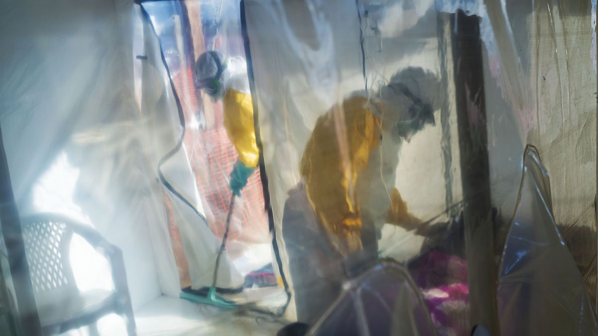 FILE - In this July 13, 2019 file photo, health workers wearing protective suits tend to an Ebola victim kept in an isolation cube in Beni, Congo. 