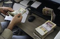 A currency exchange bureau worker counts US dollars, in downtown Tehran, Iran