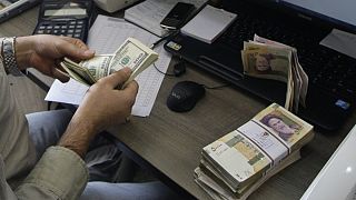 A currency exchange bureau worker counts US dollars, in downtown Tehran, Iran
